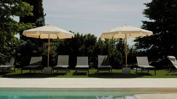 Une piscine avec des chaises longues et des parasols.