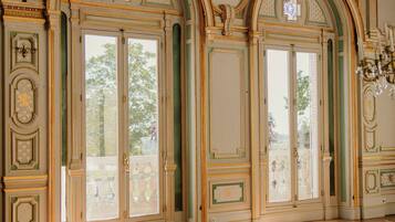 Une pièce spacieuse, ornée de moulures décoratives, dotée de grandes fenêtres et d’un sol à motifs.