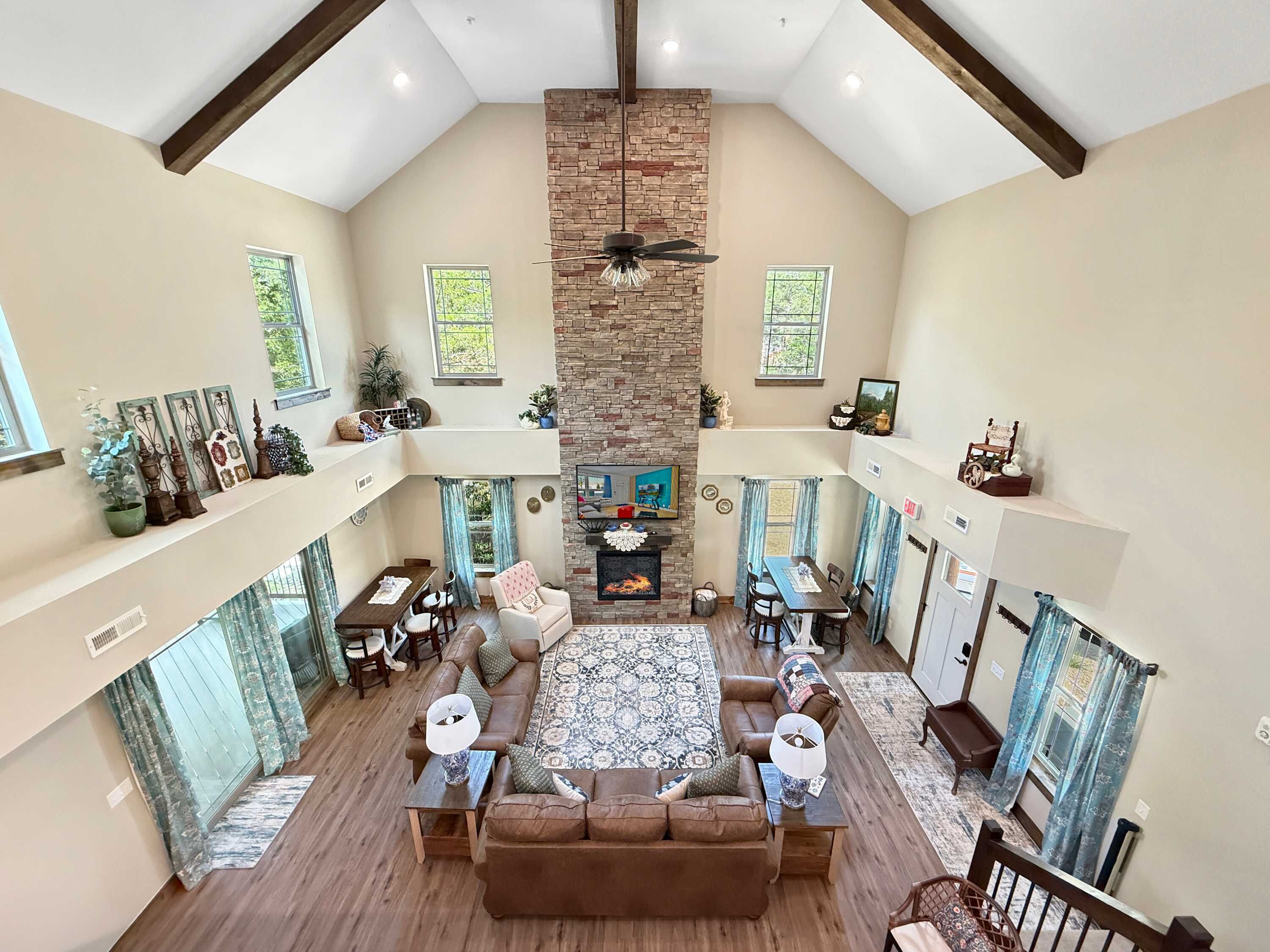 A spacious living area with a high ceiling, a fireplace, and a television.