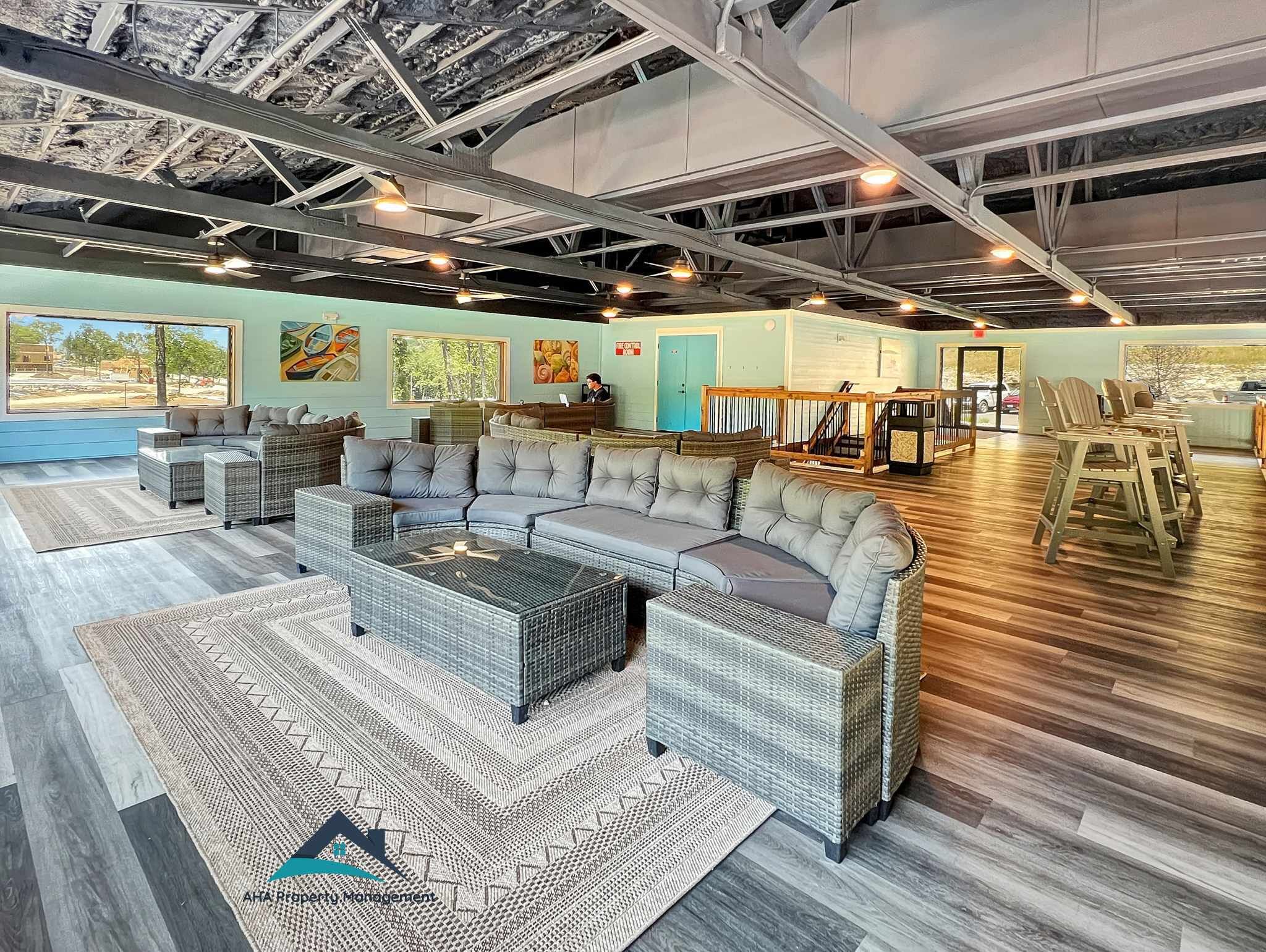 A spacious lounge area with a large sectional sofa, wicker furniture, and a view of the outdoors.