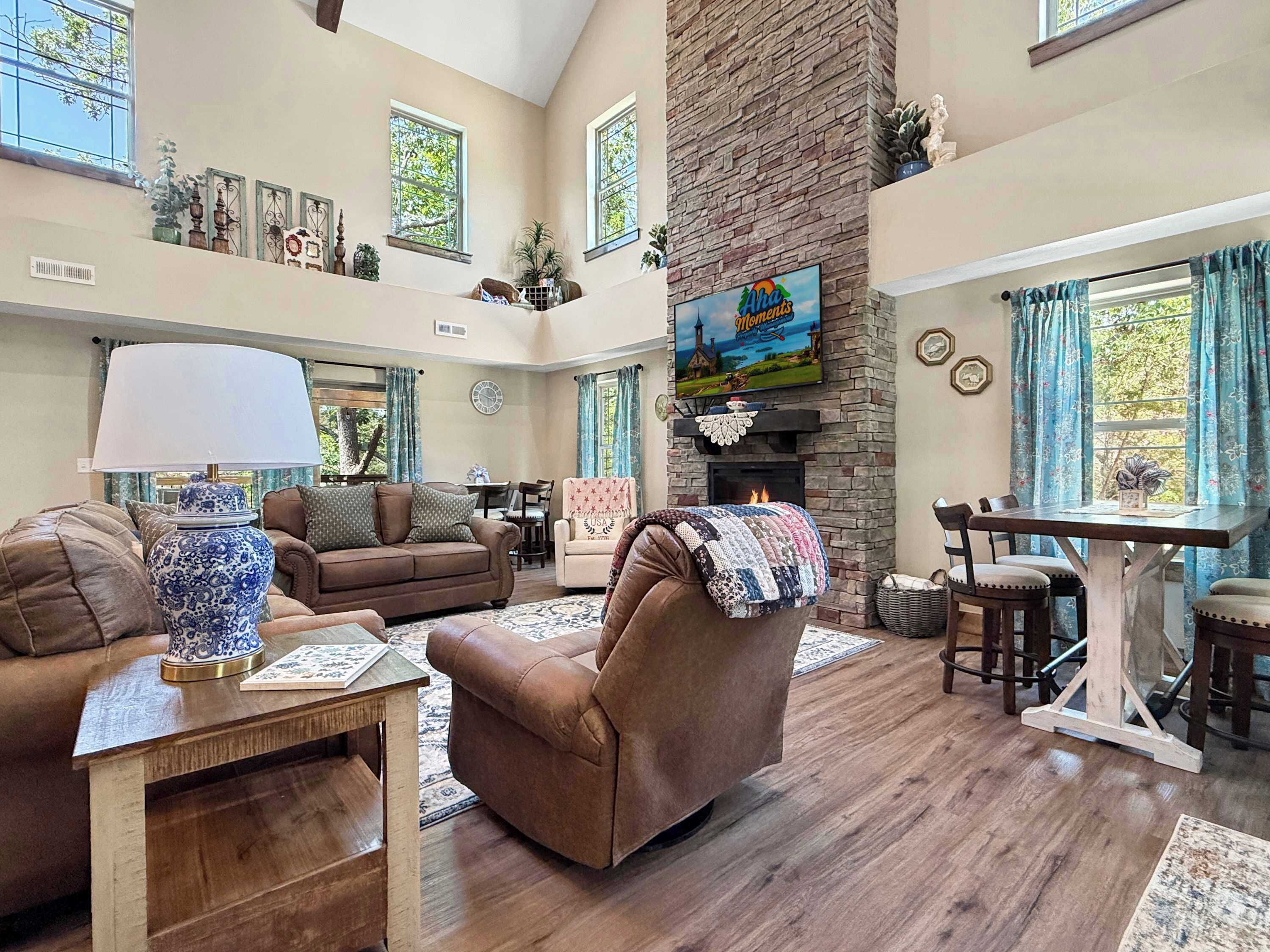 A spacious living room with a fireplace, comfortable seating, and a television mounted above it.