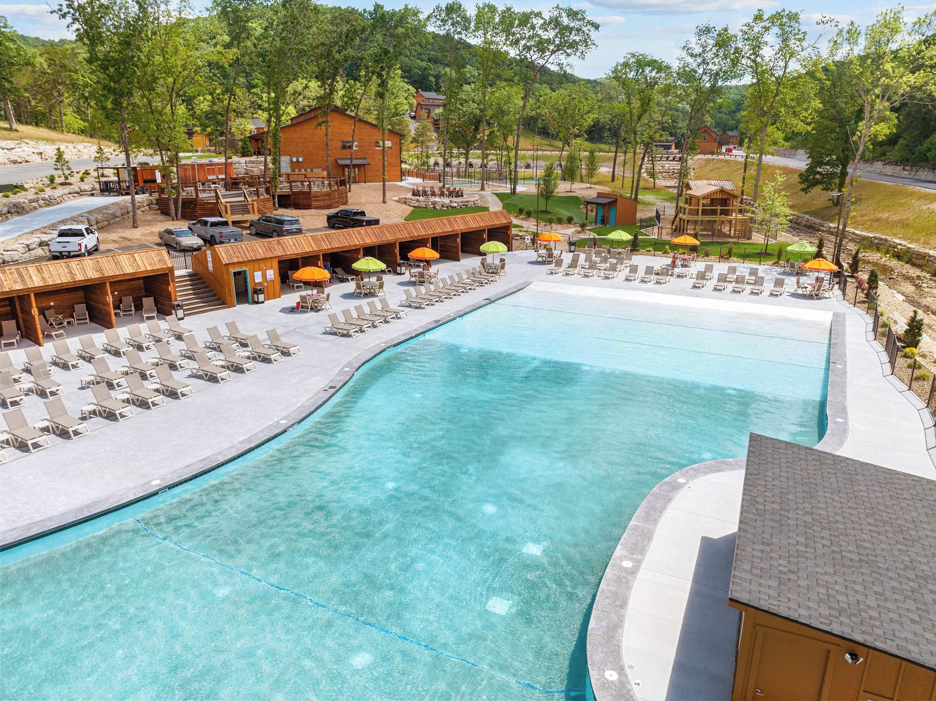 A resort with a large swimming pool, lounge chairs, and a wooden cabin structure.