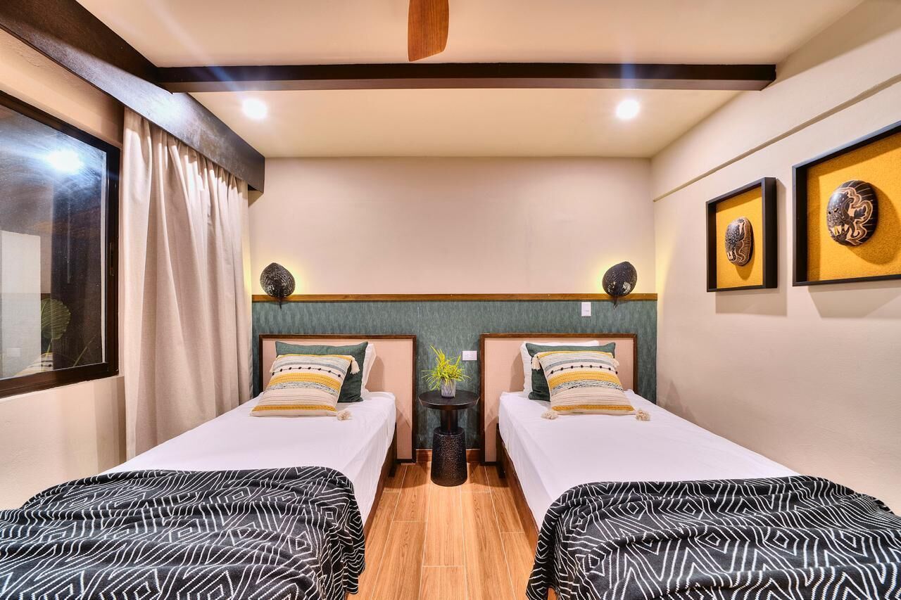 Une chambre d’hôtel avec deux lits, une petite table et un miroir.