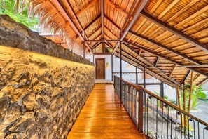 Un pasillo con techo de madera y pared de piedra, que conduce a una puerta.