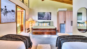 A bedroom with a bed, a sofa, a mirror, and artwork on the walls. - Deluxe Jungle View Suite (4 twin) (Puerto Viejo)