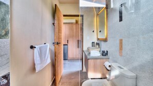 A modern bathroom with a wooden door, a sink, a mirror, and a toilet. - Deluxe Jungle View Suite (4 twin) (Puerto Viejo)
