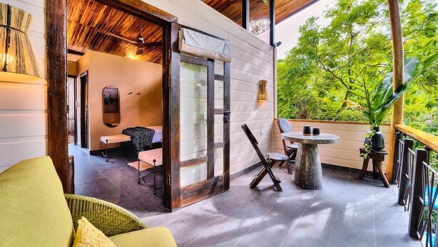 A modern outdoor patio with a dining table, chairs, and a lounge area with a sofa. - Deluxe Jungle View Suite (4 twin) (Puerto Viejo)