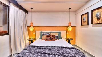 Quarto de hotel com uma cama grande, duas mesas de cabeceira, um ventilador de teto e decoração na parede.
