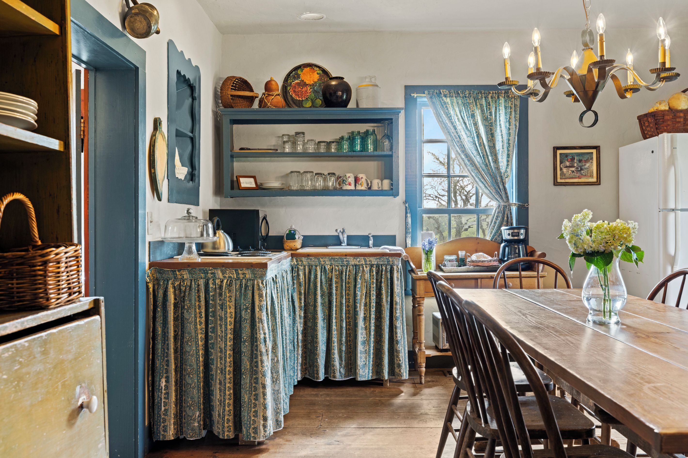 Una cocina tradicional con una mesa de madera, sillas y una araña.