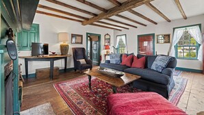Ein gemütliches Wohnzimmer mit Holzbalkendecke, einer Couch, einem Couchtisch und einem Fernseher.