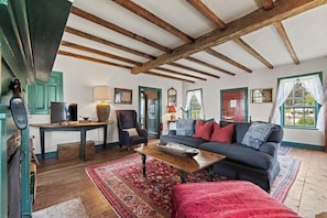 A cozy living room with a wooden ceiling, a sofa, a coffee table, and a television. - A 1787 home older than the country it stands in (Fredericksburg)