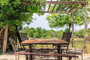 An outdoor dining area with a wooden pergola, metal chairs, and a table. - A 1787 home older than the country it stands in (Fredericksburg)