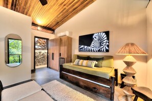 En modern inredning med en soffa, ett zebra-motiv som hänger på väggen, en rund spegel och en lampa.