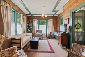 Ein gemütliches Wohnzimmer mit einer Couch, Sesseln, einem Couchtisch und einem Fernseher.