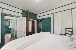 Ein Schlafzimmer mit einem Bett, einem Sessel und einer Tür zu einem Badezimmer.