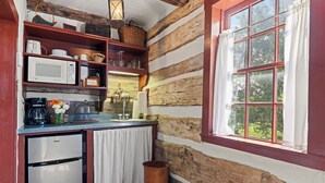 Eine rustikale Küche mit Holzvertäfelung, einem Fenster mit Vorhängen und einem Kühlschrank.