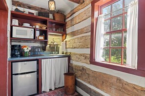 Une cuisine rustique avec un intérieur en bois, une fenêtre avec des rideaux et un réfrigérateur.