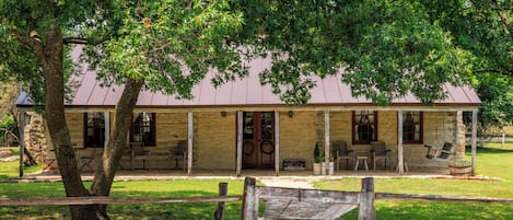 Ein rustikales Holzhaus mit Veranda, umgeben von Bäumen.