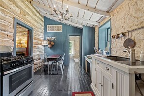 Una cocina rústica con estufa a gas, gabinetes de madera y pared de piedra.