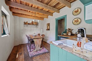 Een landelijke keuken met houten balken, een eettafel met stoelen, een gootsteen en decoratieve borden aan de muur.