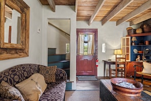 A cozy living room with a patterned sofa, a wooden coffee table, and a rustic wooden ceiling. - An 1865 limestone barn with gun-slot windows (Fredericksburg)