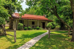 A rustic house with a stone pathway leading to the entrance, surrounded by lush greenery. - An 1847 cabin, among the area's oldest homes (Fredericksburg)