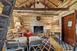 A rustic interior with a stone fireplace, wooden beams, and traditional furnishings. - An 1847 cabin, among the area's oldest homes (Fredericksburg)