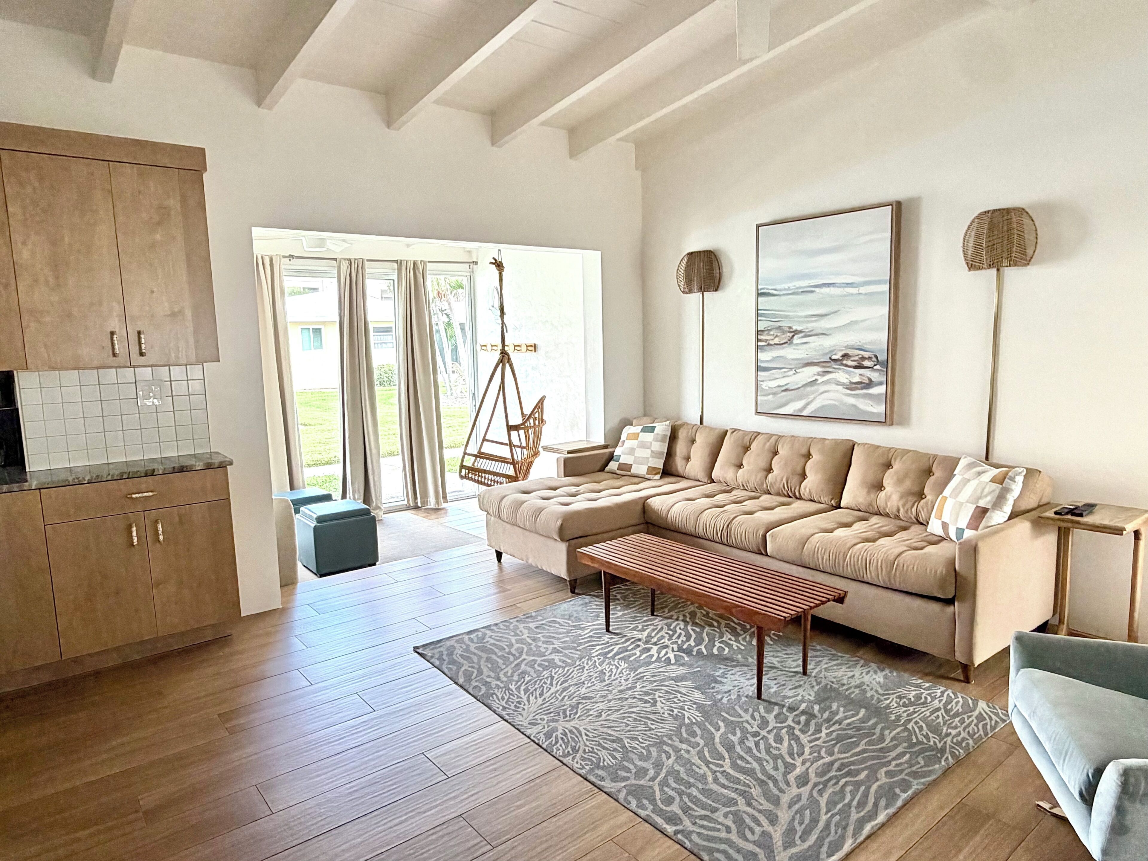 A spacious living area with a sofa, a hanging chair, and a wooden bench.