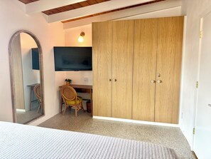 A bedroom with a bed, a wooden wardrobe, a desk with a chair, a television, and a mirror. - Siesta Key Beach Condo - Steps to Private Beach + King Bed + 2 Pools (Sarasota)