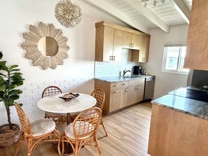 A kitchen with a round dining table, wicker chairs, wooden cabinets, and a backsplash. - Siesta Key Beach Condo - Steps to Private Beach + King Bed + 2 Pools (Sarasota)
