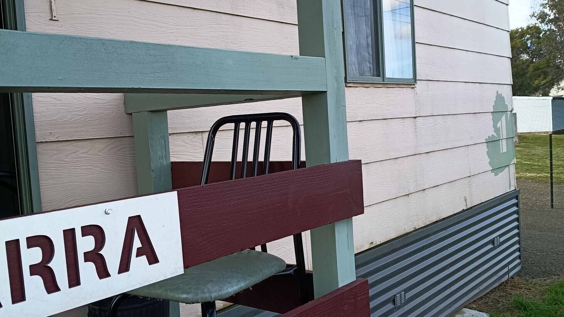 A bench with a sign reading 'IRRA' in front of a building with a window and a door.