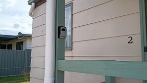 A house with a number '2' on the side, a mailbox, and a green fence.