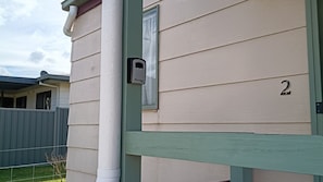 A house with a number '2' on the side, a mailbox, and a green fence.
