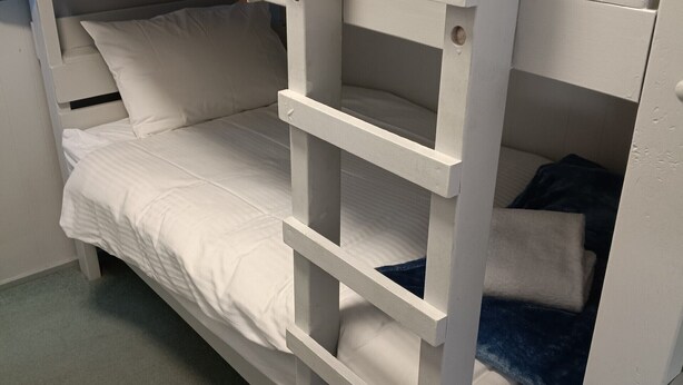 A bunk bed with white bedding and a blue blanket.