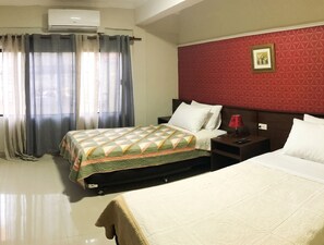 A hotel room with two beds, a red textured wall, a framed picture, and a nightstand with a lamp.