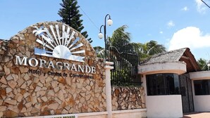 A hotel entrance with a stone wall and a sign that reads 'MORAGRANDE Hotel y Centro de Convenciones.'