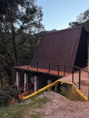 A building with a sloped roof, a wooden deck, and a metal railing.