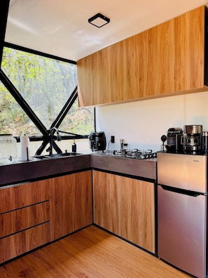 A modern kitchen with wooden cabinets, a stainless steel refrigerator, and a gas stove.