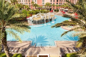 A large pool with a waterfall feature surrounded by palm trees and lounge chairs. - Queen Suite at Caribe Royale Orlando - Sports Court & Resort Fun Included! (Orlando)