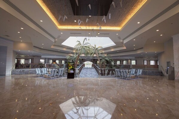 A spacious lobby with a high ceiling, a central staircase, and a large skylight. - Queen Suite at Caribe Royale Orlando - Sports Court & Resort Fun Included! (Orlando)