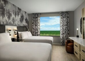 A hotel room with two beds, a desk, a chair, a nightstand, a lamp, and a large window with a view of greenery. - Queen Suite at Caribe Royale Orlando - Sports Court & Resort Fun Included! (Orlando)