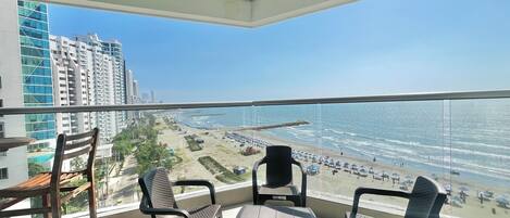 Ein Balkon mit Blick auf den Strand, Stühlen und einem Tisch.