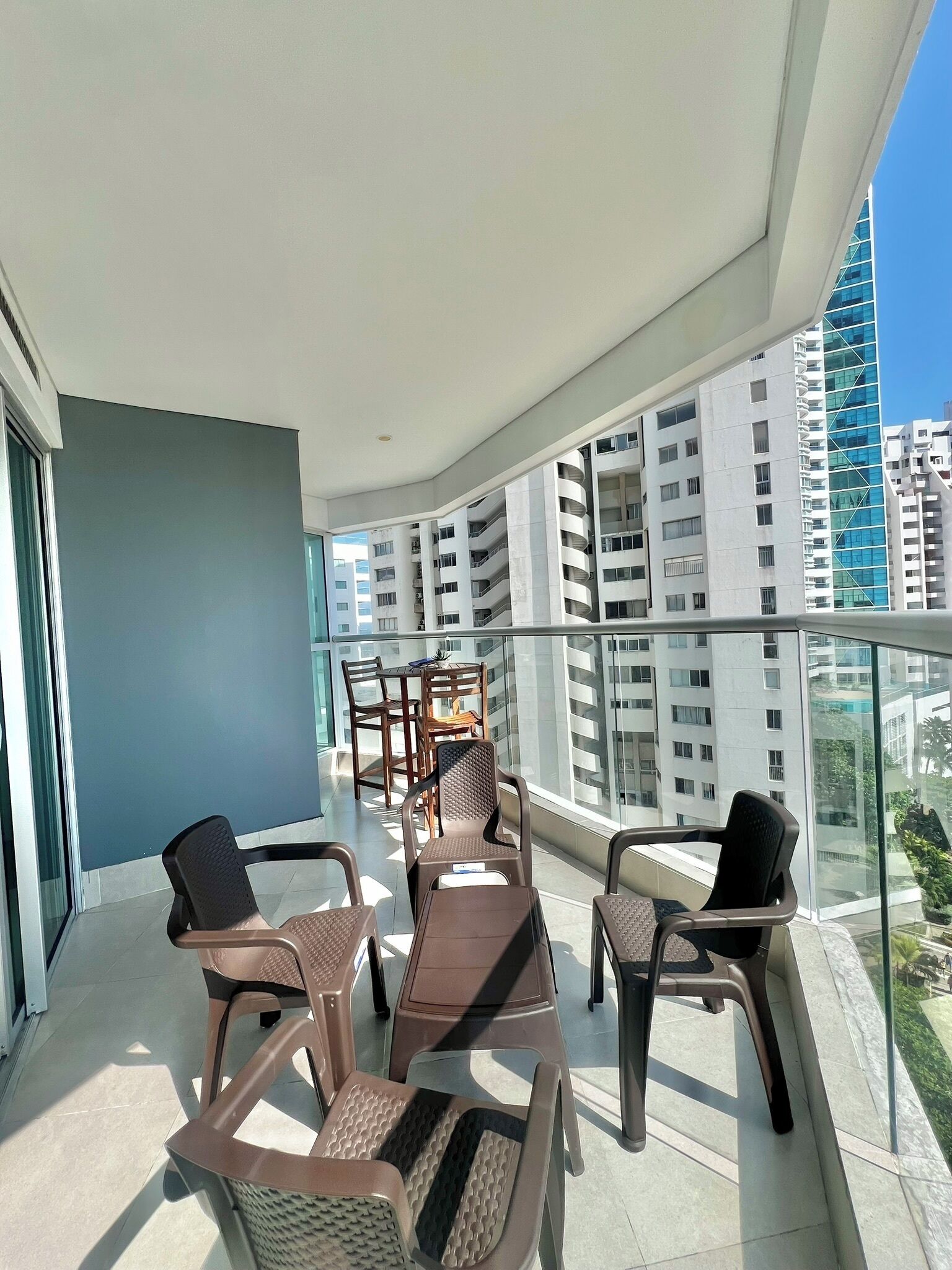 Een balkon met tafel en stoelen, met uitzicht op een stadsbeeld met moderne gebouwen.