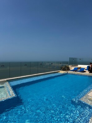 Ein Swimmingpool mit klarem, blauem Wasser, einer Glaskuppel und blauen Liegestühlen.