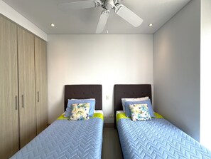 Ein Schlafzimmer mit zwei Einzelbetten, einem Deckenventilator und einem Kleiderschrank.