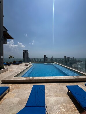 A rooftop pool with clear blue water, surrounded by lounge chairs and potted plants. - 2-Bedroom Apartment in Bocagrande (Near the Historic Center) (Cartagena de Indias)