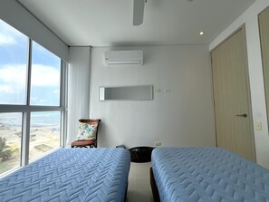 Ein Zimmer mit zwei Betten, einem Sessel, einem Fenster mit Blick und einer Tür.