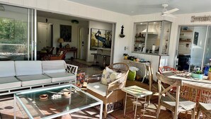 A sunlit room with a glass table, wicker furniture, and a view of the outdoors. - Shovel Sand, Not Snow! You've found your Sanibel Island retreat! Secluded near-beach Strangler Fig home has it all.  Pet-friendly, too! (Sanibel)