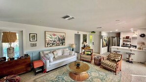 A living room with a sofa, armchairs, a coffee table, and a kitchen area with a refrigerator and cabinets. - Shovel Sand, Not Snow! You've found your Sanibel Island retreat! Secluded near-beach Strangler Fig home has it all.  Pet-friendly, too! (Sanibel)