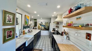 A modern kitchen with a central island, pendant lighting, and decorative wall art. - Shovel Sand, Not Snow! You've found your Sanibel Island retreat! Secluded near-beach Strangler Fig home has it all.  Pet-friendly, too! (Sanibel)